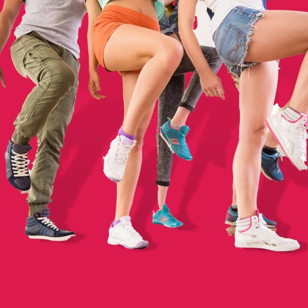 a group of people standing in a line with knees in the air coordinated dancing